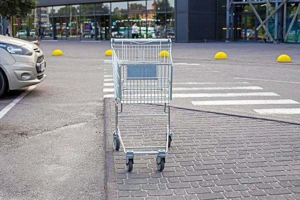 Süpermarketin yanındaki otoparkta metal market arabası var.