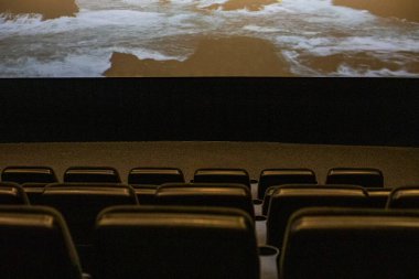 Sinema salonu film gösterimi sırasında ışıkları kapalı.