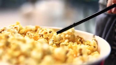 Kız kokteyl pipetiyle patlamış mısır alıyor.