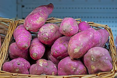 Marketteki bir konteynırda olgun mor patatesler.