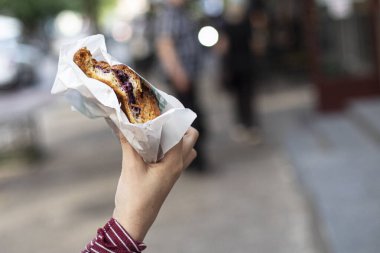 Dışarıda kruvasan yiyen bir kız. Sokakta atıştırmalık