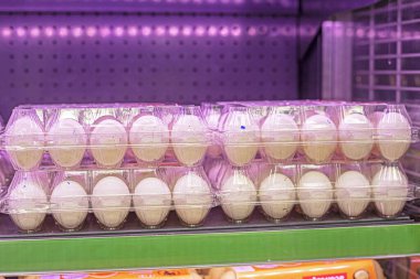 Süpermarketteki buzdolabında şeffaf bir paketin içinde beyaz yumurtalar. Ekonomik kriz