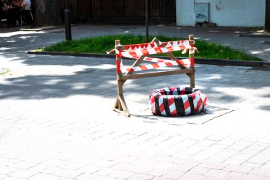 hole in the roadway in the city fenced with red tape
