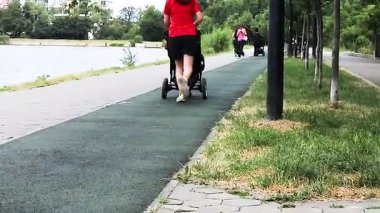 Genç anne bebek arabasında bir çocukla koşu bandında koşuyor. Günaydın. 