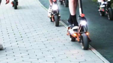 Gençler bir grupta el fenerleriyle elektrikli scooter kullanıyorlar..