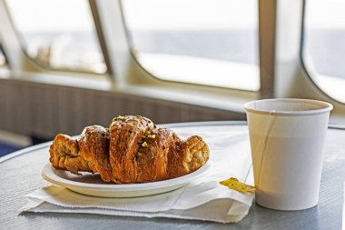 Bir yolcu gemisinde tek kullanımlık fincanda çay ile kruvasan. Sabah atıştırması