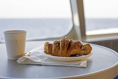 Bir yolcu gemisinde tek kullanımlık fincanda çay ile kruvasan. Sabah atıştırması