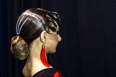 Siyah arka planda kırmızı küpe takan genç bir dansçının güzel profili. Balo dansı görüntüsü