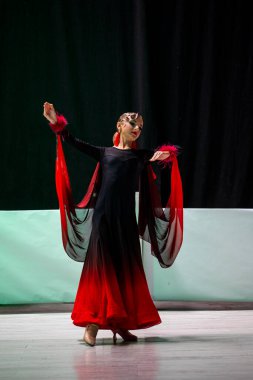 Genç dansçı, Program Standart Turnuvası 'nda siyah ve kırmızı elbiseyle performans sergiliyor..