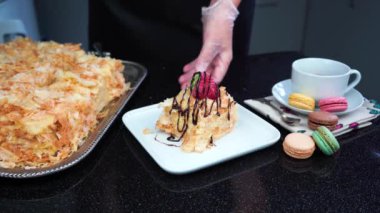 Puff pastry cake poured with chocolate, colourful macarons and a cup of tea, 4K