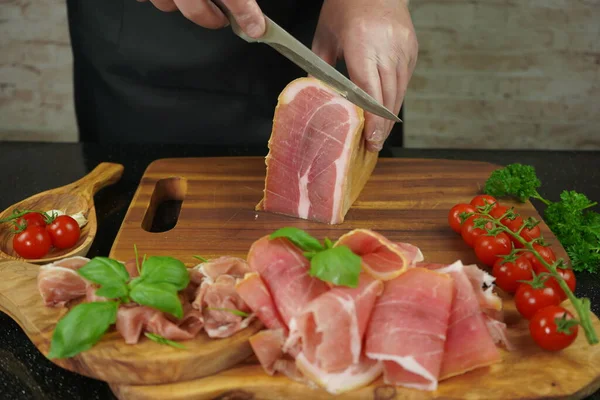 Cutting slices of dry ham on a wooden board, meat slices on wooden board concept