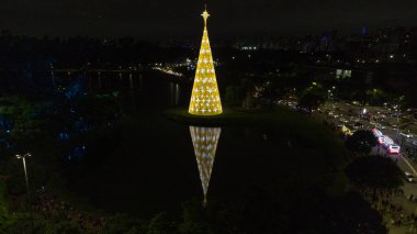  Ibirapuera Parkı 'ndaki Noel Ağacı' nın havadan görünüşü, suda bir sunum ve birçok insan izliyor.