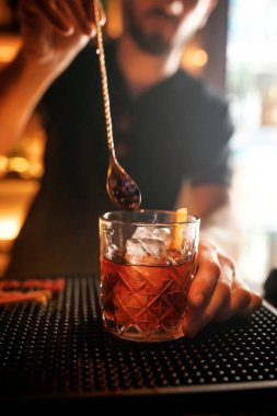 Bir barmen barda bir kokteyl hazırlar. Bir bardağın yakın çekimi..