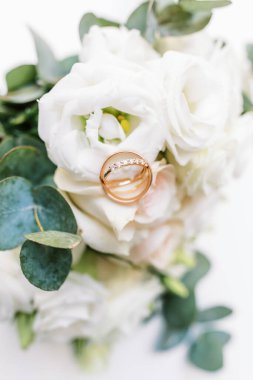 Yeni evlilerin yüzükleri zarif bir buket çiçeğin üzerinde duruyor, düğün temalı..