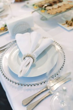 Güzel katlanmış bir peçete beyaz bir tabakta, bir kutlamada sofra kurulacak..