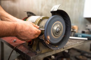 Adam atölyedeki dairesel metal tekerlek üzerinde çalışıyor..