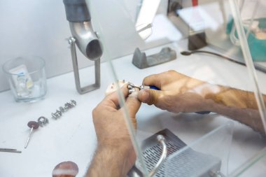 Diş sağlığı kliniğinde diş aletlerini tutan bir dişçinin eline yakın çekim