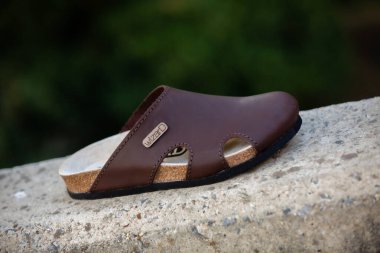 Kahverengi ve beyaz deri sandaletlerin yakın plan çekimi.