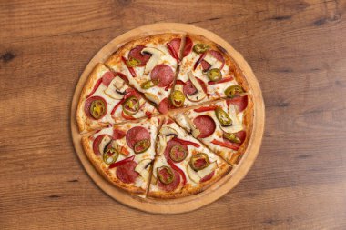 Tahta masada salamlı, biberli ve mantarlı pizza.