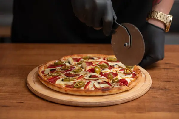 Şef masada pizza kesiyor.