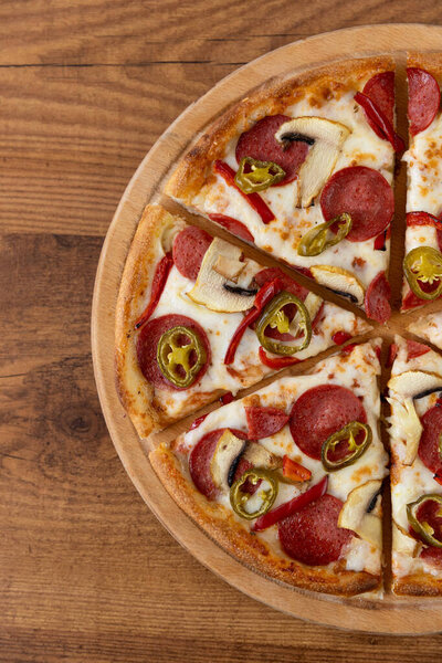 Пицца с салями, перцем и грибами на деревянном столе