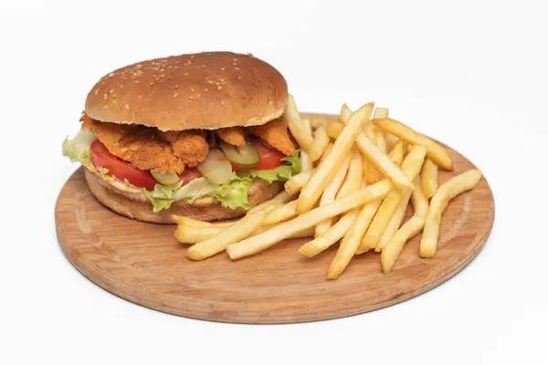 Kızarmış tavuk burger, patates kızartması ve beyaz arka planda izole edilmiş ahşap tabakta salata..