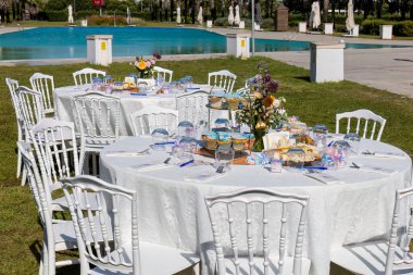 Çiçekli bir düğün masası, bardaklar, bardaklar ve bahçede mumlarla dolu bir masa..