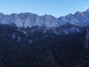 Beautiful landscape with high rocks with illuminated peaks, stones in mountain lake, reflection, blue sky and yellow sunlight in sunrise. Nepal. Amazing scene with Himalayan mountains. Himalayas.High