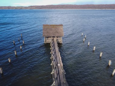 Tarafsız yoğunluğa uzun süre maruz kalmak doğal minimalist deniz manzarasını filtreler. Rıhtımda bekleyen yağmurluk giymiş bir adam. Maruz kaldıkları sırada teknelerin görüntüsü. Rıhtım ve tekneler. Yüksek kalite fotoğraf