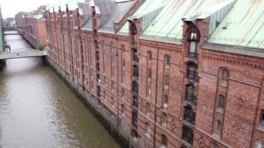 Speicherstadt 'ta Hamburg, Almanya' da köprüleri olan eski kırmızı tuğlalı binalar. Yüksek kalite FullHD görüntüsü. Eski şehrin kanallarında ve rıhtımlarında uçuyor.