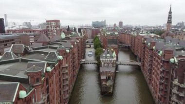 Speicherstadt 'ta Hamburg, Almanya' da köprüleri olan eski kırmızı tuğlalı binalar. Yüksek kalite FullHD görüntüsü. Eski şehrin kanallarında ve rıhtımlarında uçuyor.