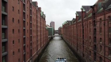 Speicherstadt 'ta Hamburg, Almanya' da köprüleri olan eski kırmızı tuğlalı binalar. Yüksek kalite FullHD görüntüsü. Eski şehrin kanallarında ve rıhtımlarında uçuyor.