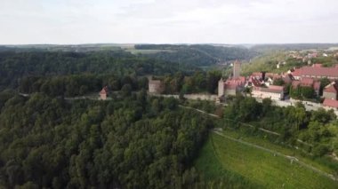 Alsace Şarap Yolu 'nun karakteristik hava manzarası, ön planda yeşil üzüm bağları ve uzaktan görülen küçük tarihi kasaba. Kamera olgunlaşan sarmaşıkların üzerinde alçaktan uçuyor. Yüksek kaliteli FullHD görüntüler