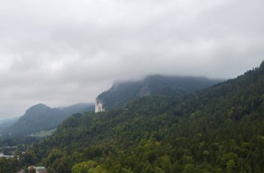 Almanya 'daki yüksek dağlardan görülen birkaç dağ tabakası hafif sis ile muhteşemdir. Yüksek kaliteli fotoğraf. Bavyera Alp dağlarının sisli ve ağaçlı göl manzaralı görüntüsü.