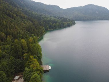 Alp gölünün muhteşem manzarası kristal berrak yeşil su ve mükemmel mavi gökyüzü. Zell am See 'deki Zeller Gölü ile Alpler' deki güzel dağ manzarasının panoramik görüntüsü. Yüksek kalite fotoğraf