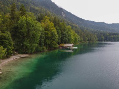 Gün batımında manzaralı göl manzaralı Alman ahşap yazlığı. Yüksek kalite fotoğraf. Dağlarda bir gölün kıyısında bir ev. Bavyera Alp Dağları 'nda hayat. Kimse yok.