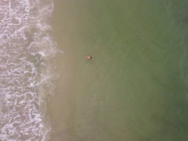 Yüzen ve rahatlayan bir adamın yan görüntüsü. Stand Up Paddle SUP 'de denizdeki sportif adam. Aktif ve sağlıklı yaşam kavramı doğayla uyum içinde. Yüksek kalite fotoğraf