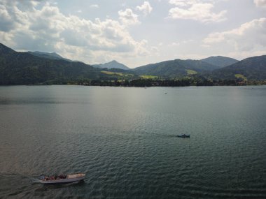 İsviçre 'deki Lugano Gölü' nün panoramik manzarası. Etrafı dağlarla çevrili ve gökyüzünün altında küçük tekneler var. Yüksek kalite fotoğraf