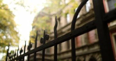 Iron fence guarding old mansion with golden trees in autumn season. High quality 4k footage