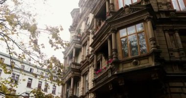 Looking up a old 1900s style stone building in city during bright day. High quality 4k footage