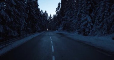 Dark gloomy winter street in snow covered forest after cold night. High quality 4k footage