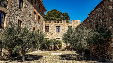 Konforlu avlu, büyüyen zeytin ağaçları olan antik binalarla çevrili.