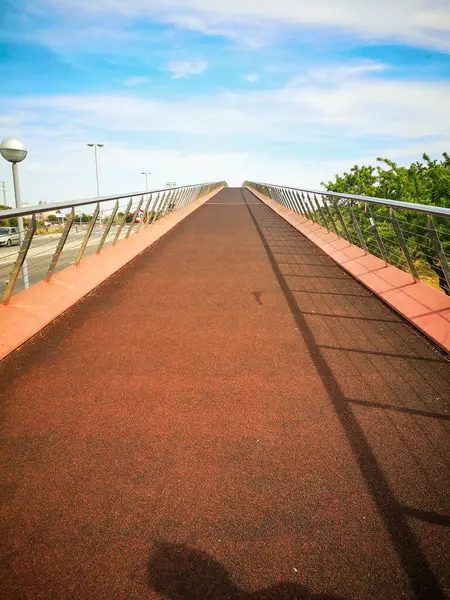 red path of the pedestrian bridge extending into the blue sky