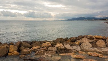 Kayalık bir kıyısı ve küçük bir adası olan güzel bir deniz manzarası.