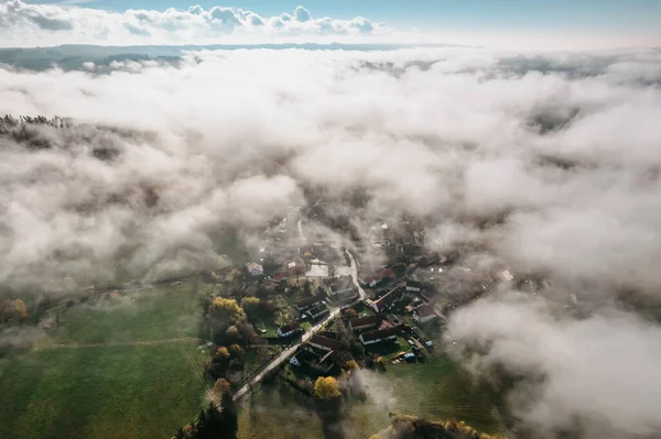 Aerial view of small village in fog.Top view of traditional housing estate in Czech.Looking straight down with satellite image style.Houses from above,rooftop real estate concept.Misty fall morning.
