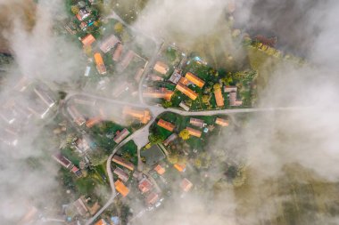 Aerial view of small village in fog.Top view of traditional housing estate in Czech. Looking straight down with a satellite image style.Houses from above, real estate concept.Country road urban scene.