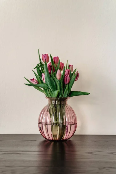 Beautiful spring decoration.Pink purple tulips in glass vase.Fresh tulip flowers bouquet.View with copy space.Greeting card.Woman Mothers Day.Minimalistic bouquet of flowers.Home decoration.