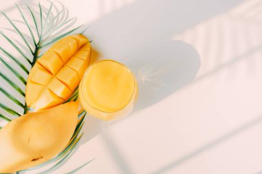 Üst ve düz yaz meyveleri tropikal yaprak ve beyaz arka plan gölgeli mango dilimi ve meyve suyu ile uzanır.