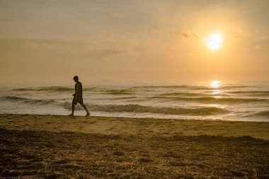 Sahilde koşan siluet adam gün doğumu ve deniz altyapısı ile