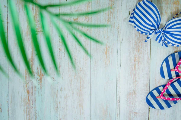 Web afişi ve düz bir yaz mevsimi mayolu ve plaj aksesuarlı klasik mavi ahşap arka planda.